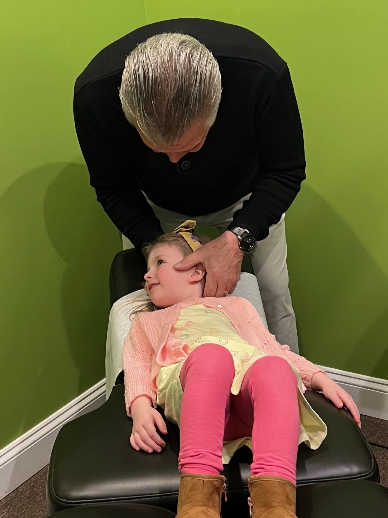 Dr. Micheil Hanczaryk adjusting a young girl in pink on the table