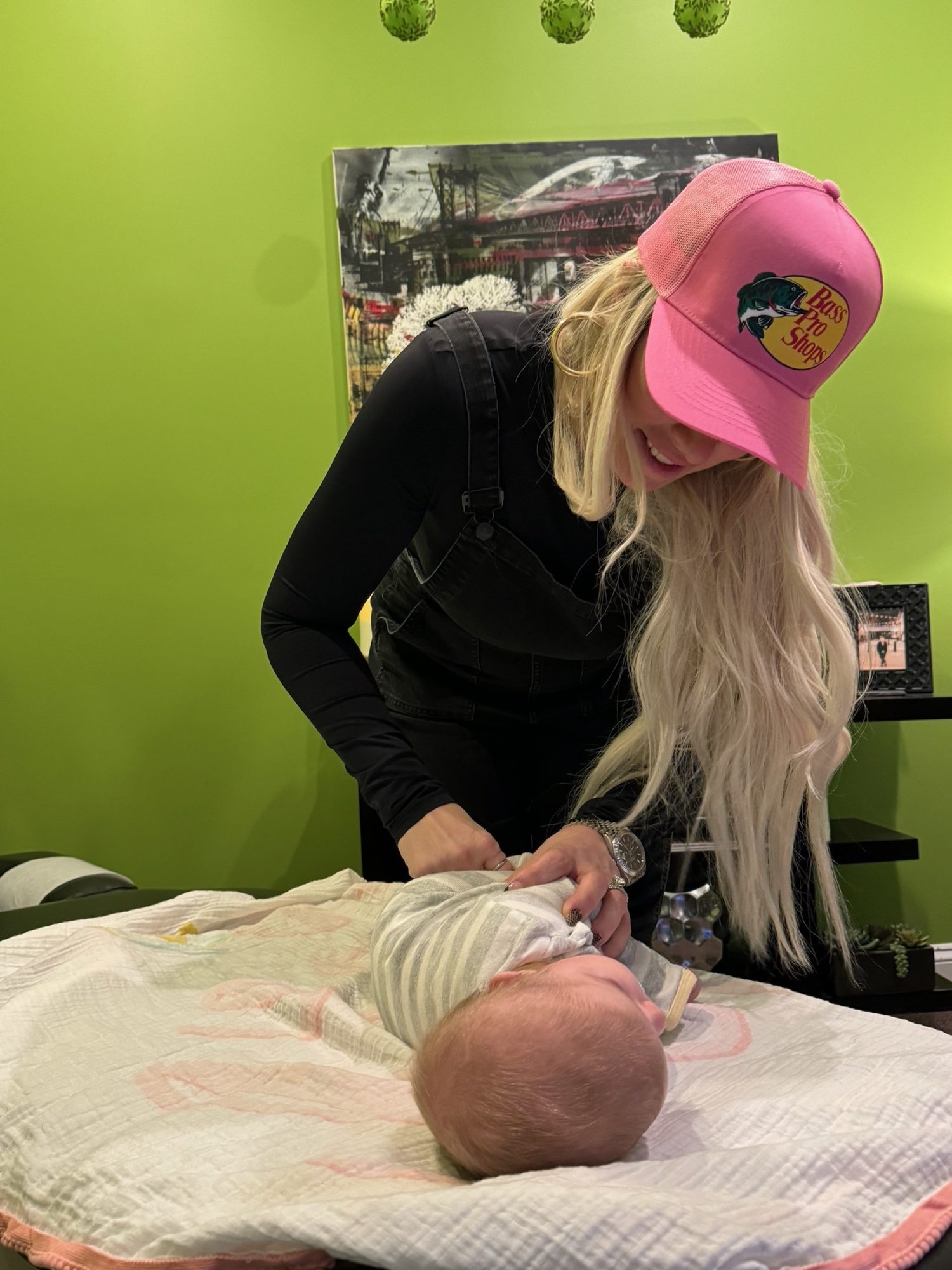 Dr. Christine in a pink cap checking a newborn in the green kids room