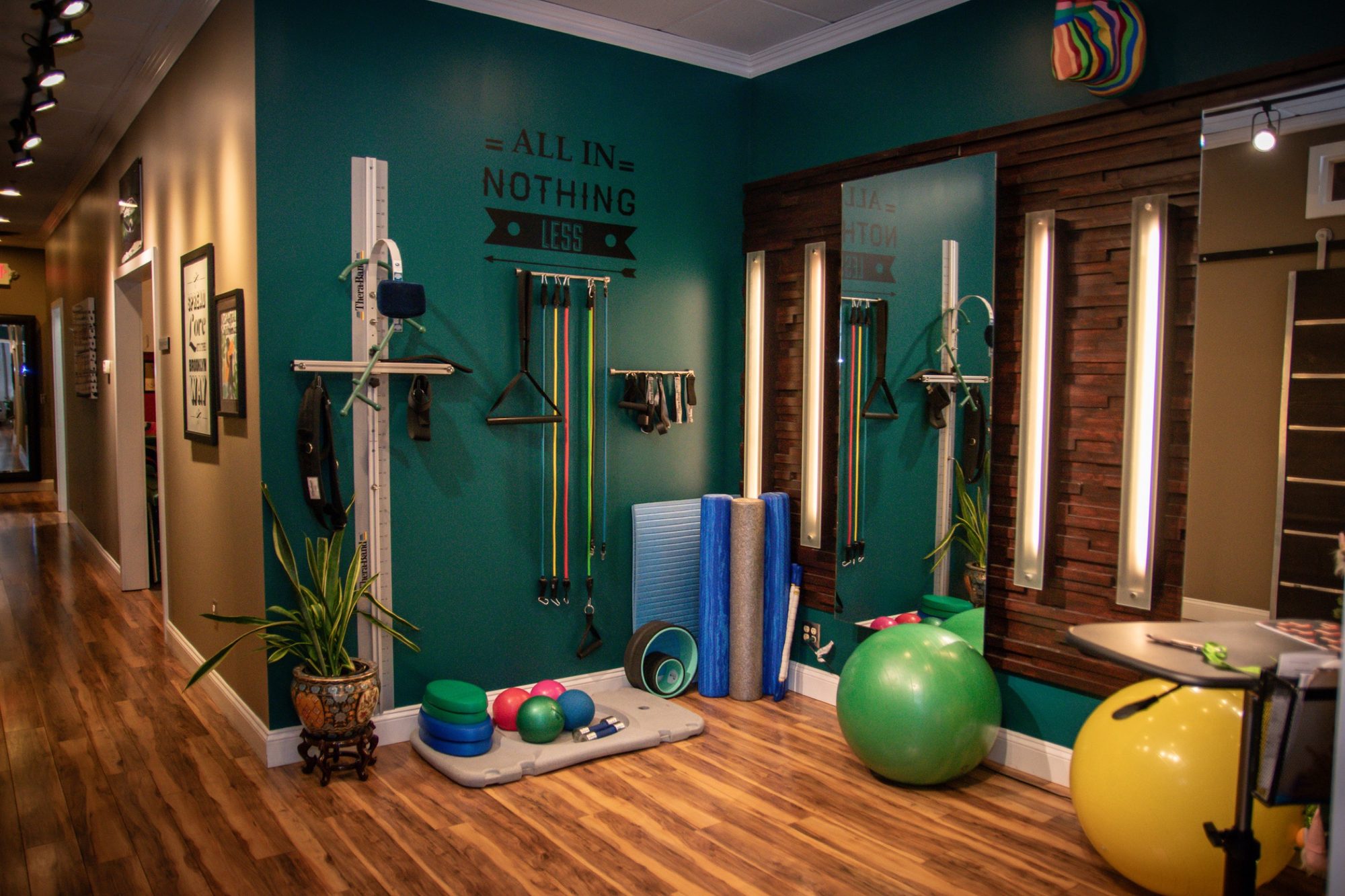 The rehabilitation room: teal walls, posture stations, foam rollers, and stability balls